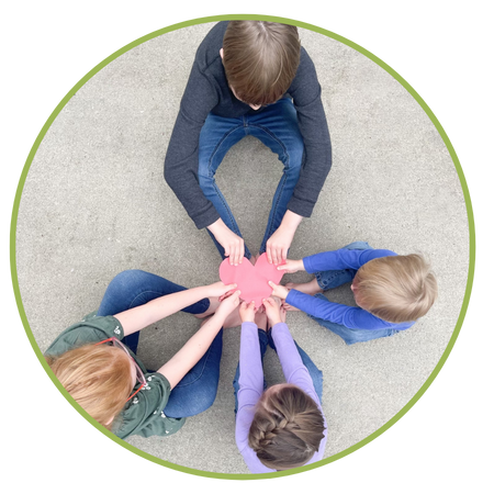 Four children sitting in a circle holding a paper heart